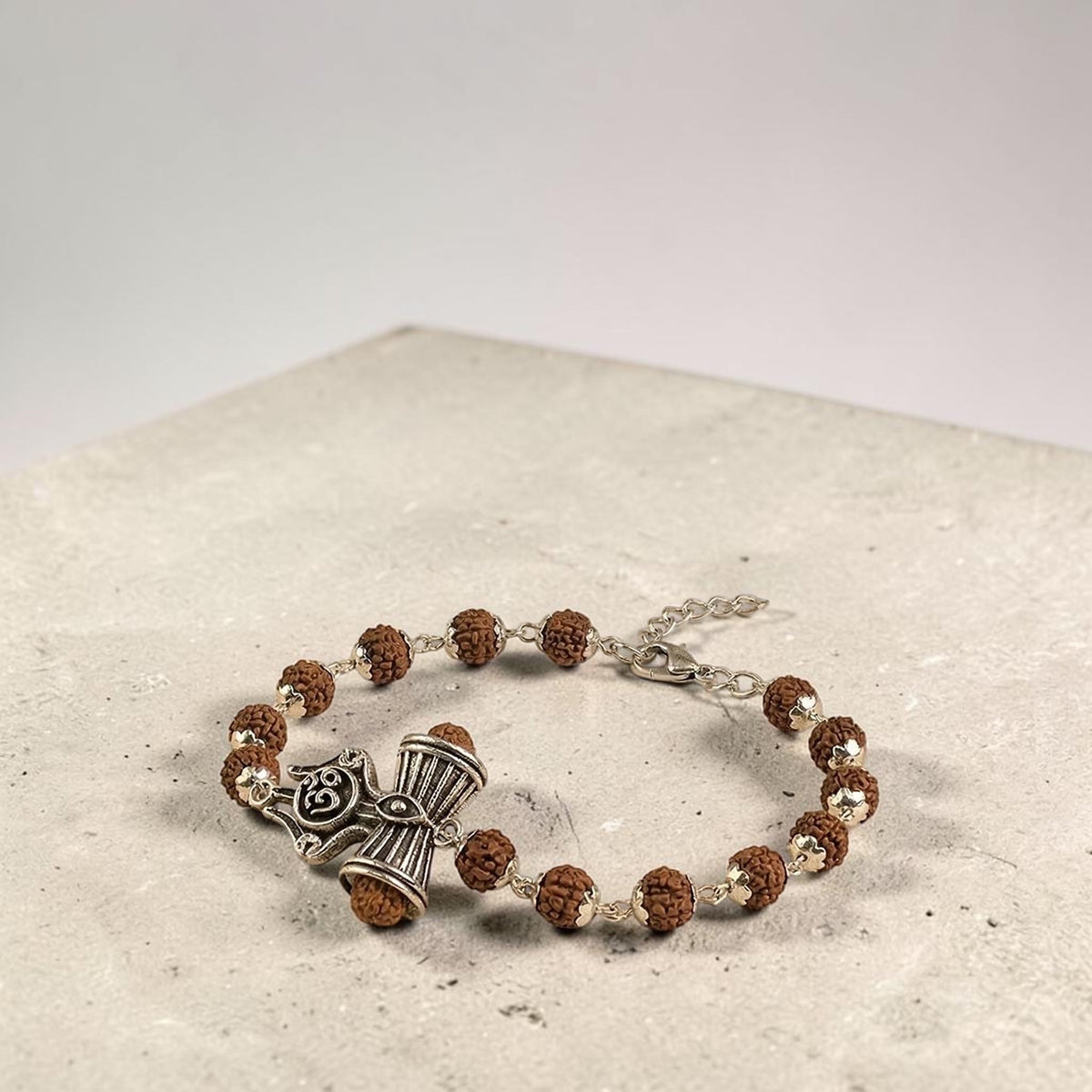 VASTUKOSHA Rinmukteshwar Siddh Rudraksha bracelet featuring silver Om, Trishul, and Damru charms on a soft fabric base.