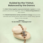 VASTUKOSHA Om Trinetra Trishul Damru Rudraksha bracelet featuring 5 Mukhi beads resting on smooth stones.