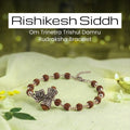 VASTUKOSHA Rishikesh Siddh Rudraksha bracelet featuring silver Om, Trishul, and Damru charms on a soft green fabric.