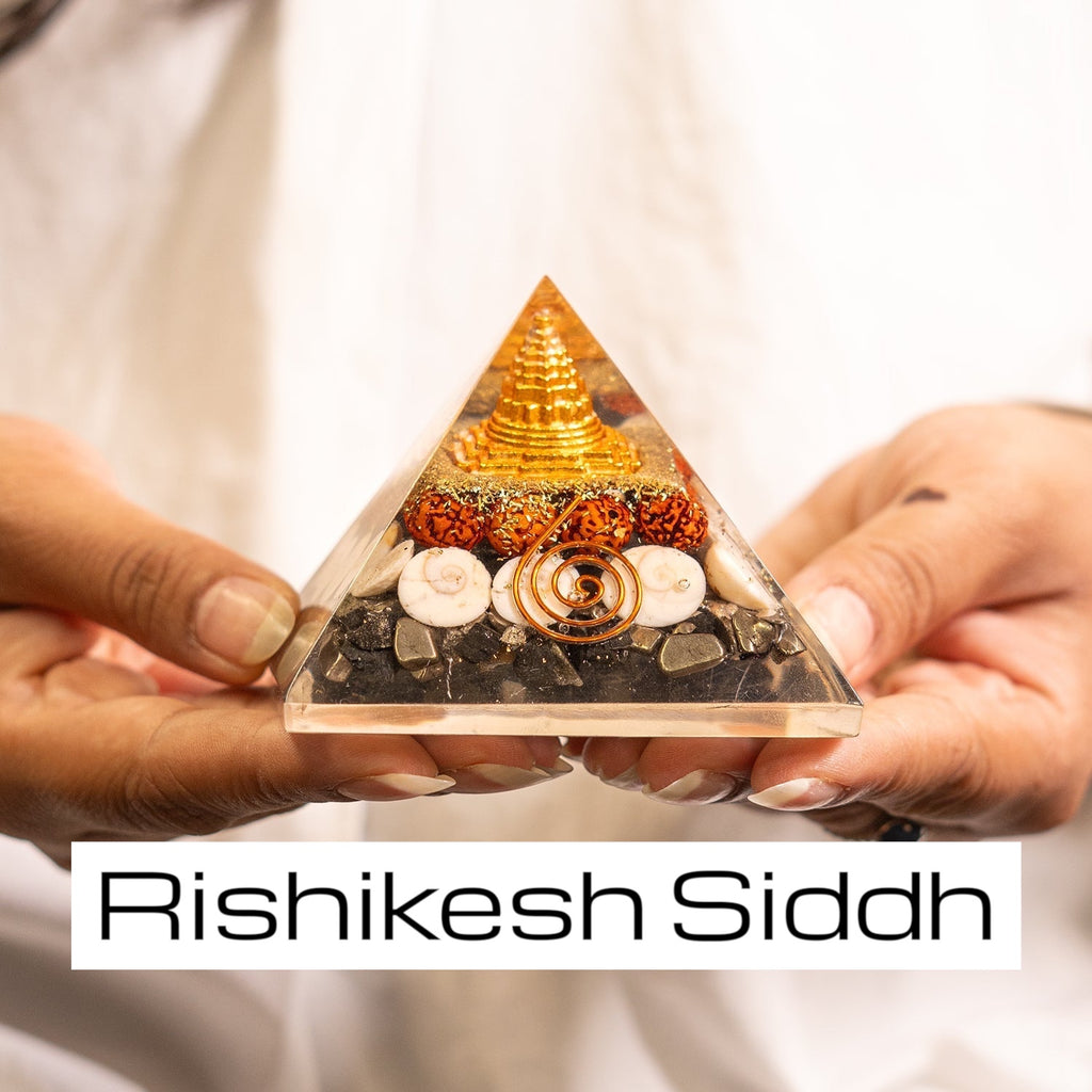 Vastukosha Rishikesh Siddh Lakshmi Yantra pyramid with gold accents, rudraksha beads, and shells held in hands.