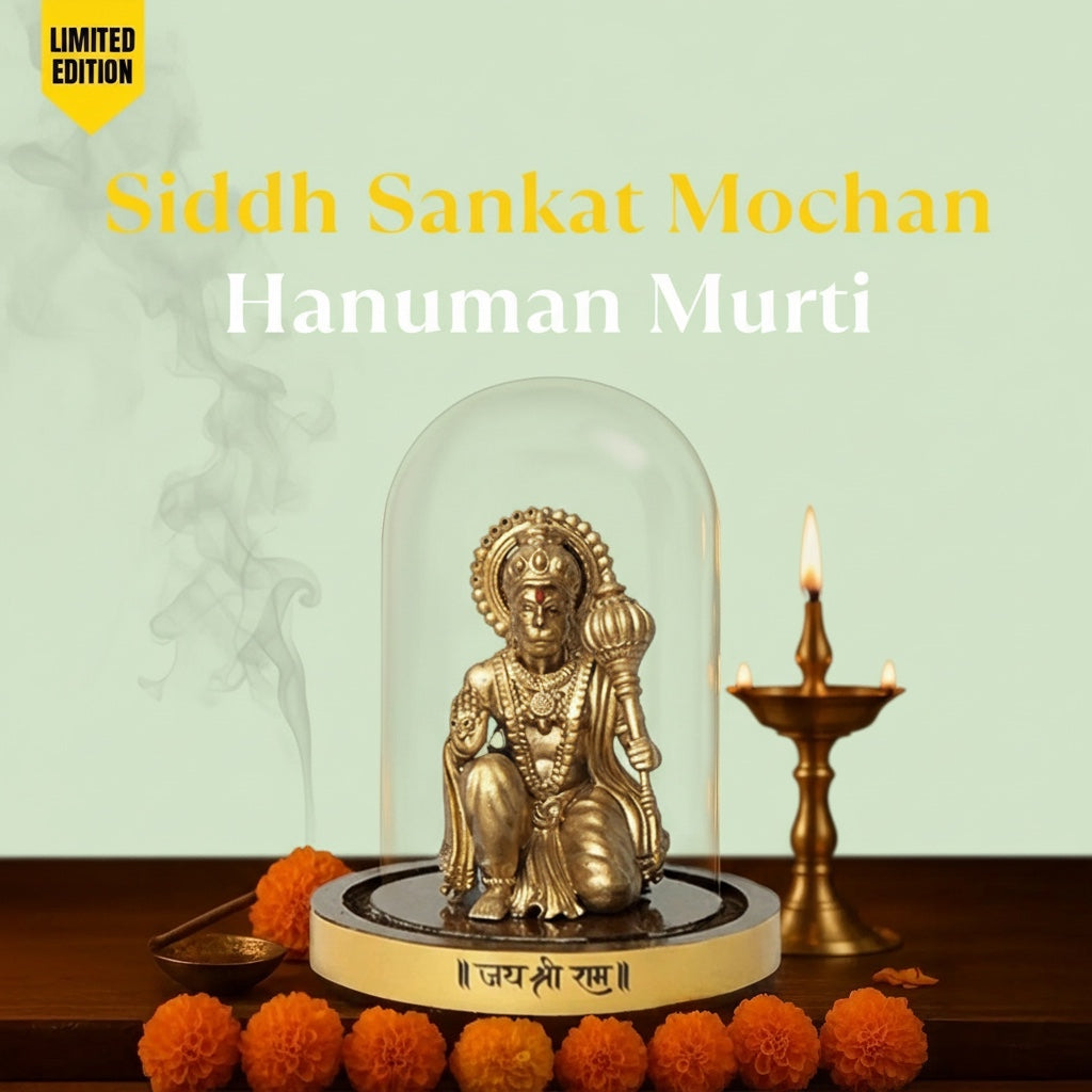 VASTUKOSHA Siddh Sankat Mochan Hanuman Murti in a glass dome with marigold flowers and a brass diya lamp.