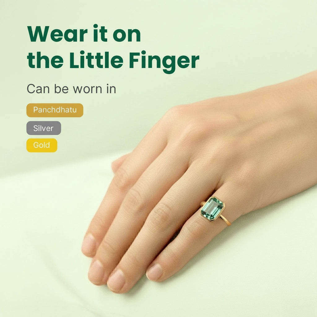 VASTUKOSHA Zambian emerald ring worn on the little finger, showcasing a green gemstone in a gold setting.